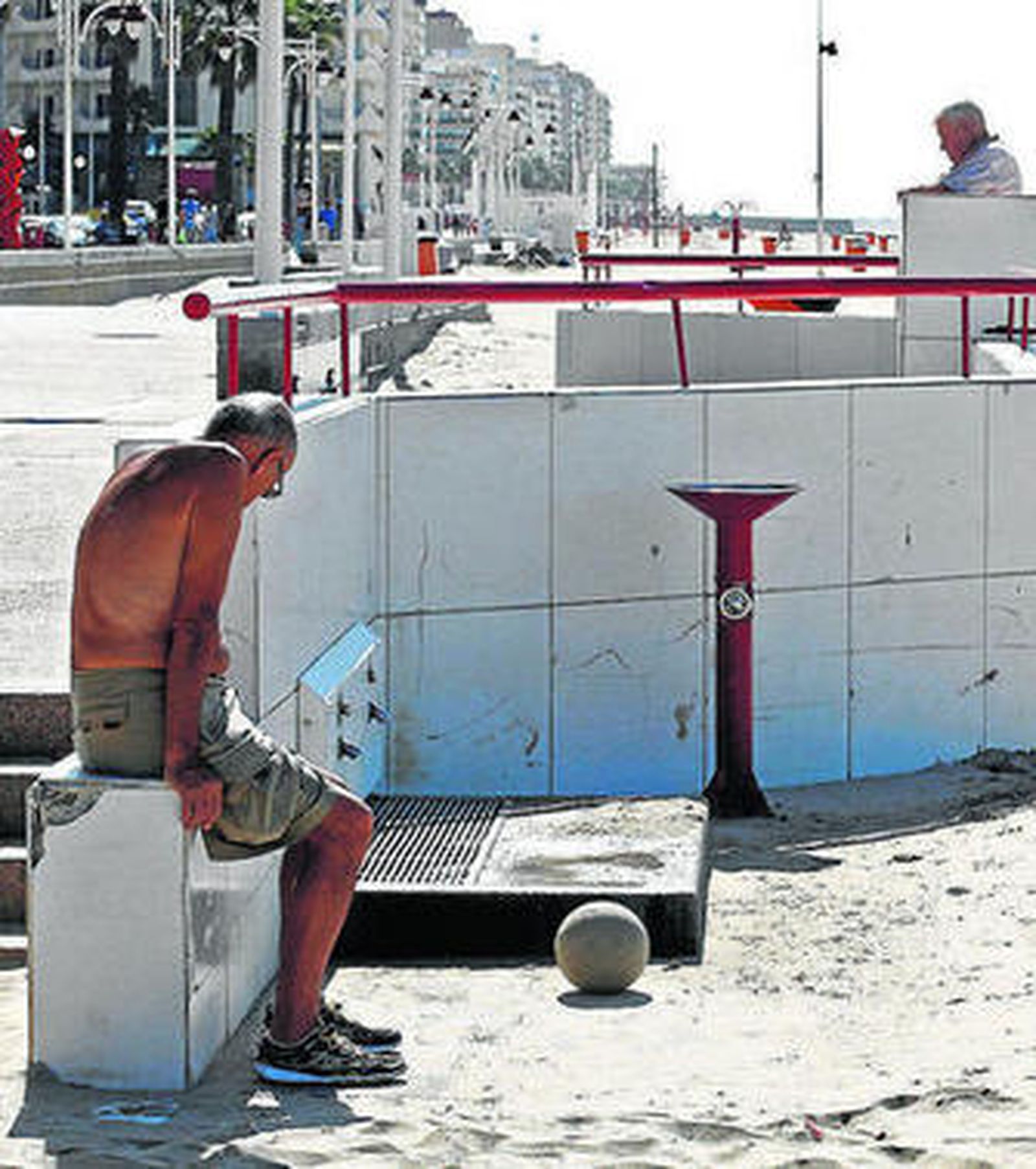 Un ciudadano descansa junto a un lavapiés de la playa.