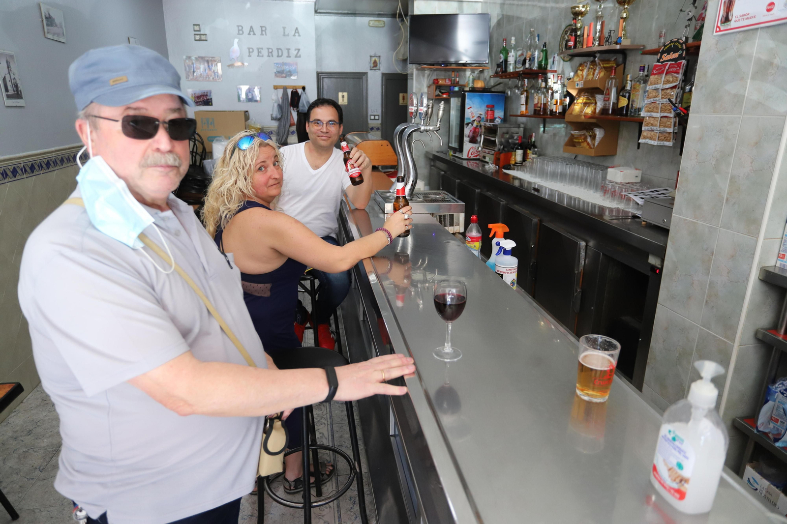 Varias personas disfrutan de sus consumiciones en la barra del bar La Perdiz.