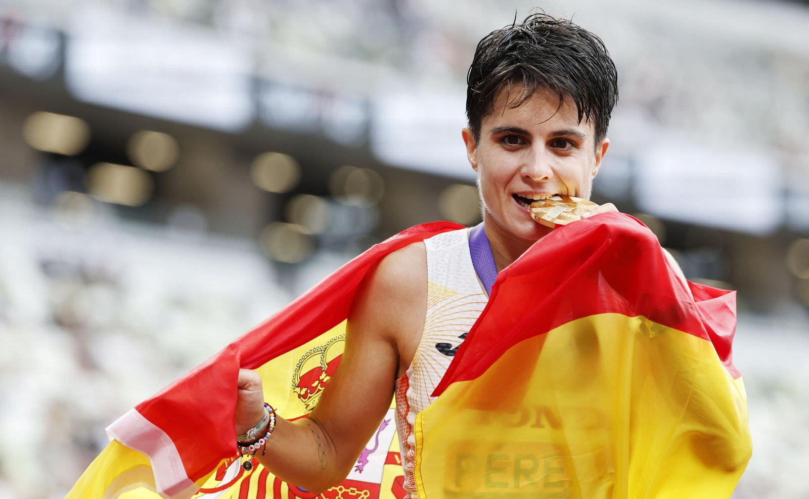 María Pérez muerde su cuarta medalla de oro envuelta en la bandera española.