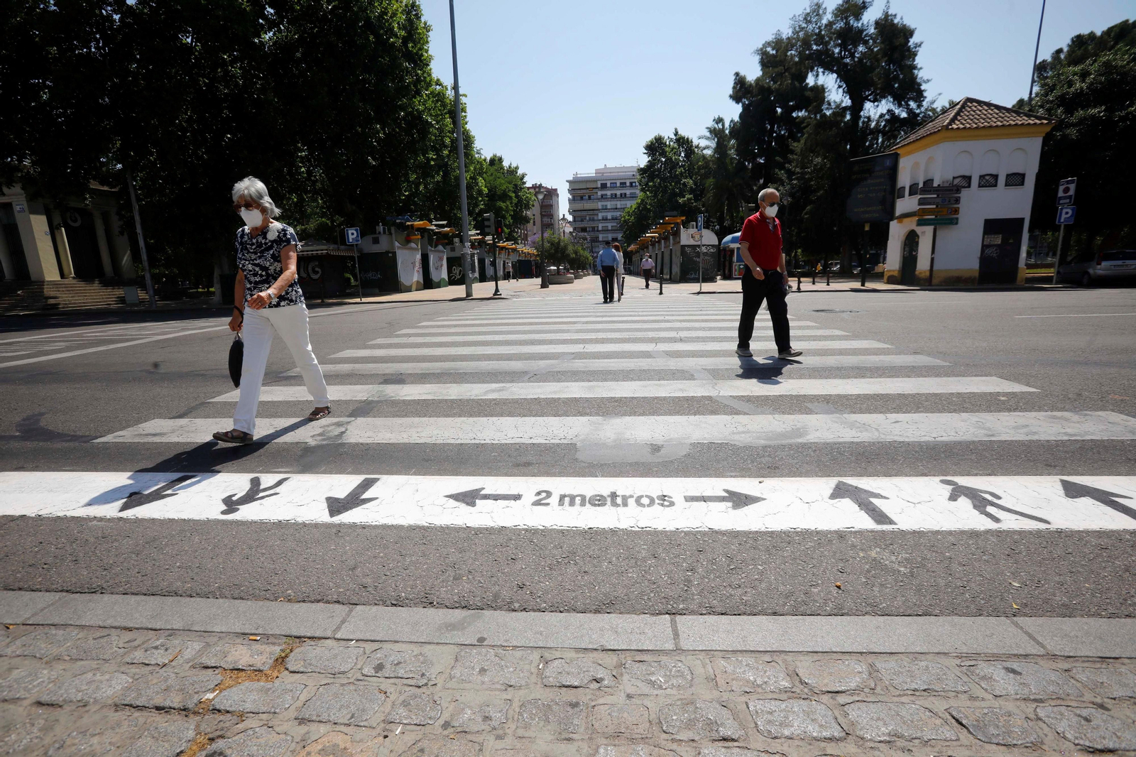 Dos personas cruzan, separados, un paso de cebra de una de las calles de la capital.
