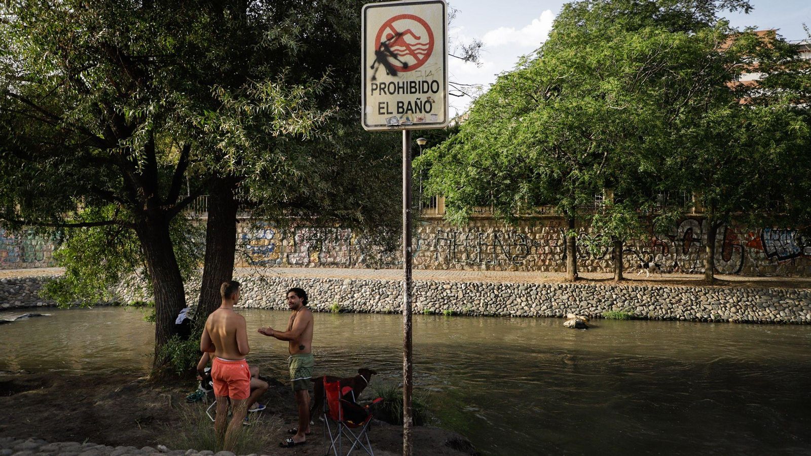 Dos jóvenes charlan junto al río Genil en bañador