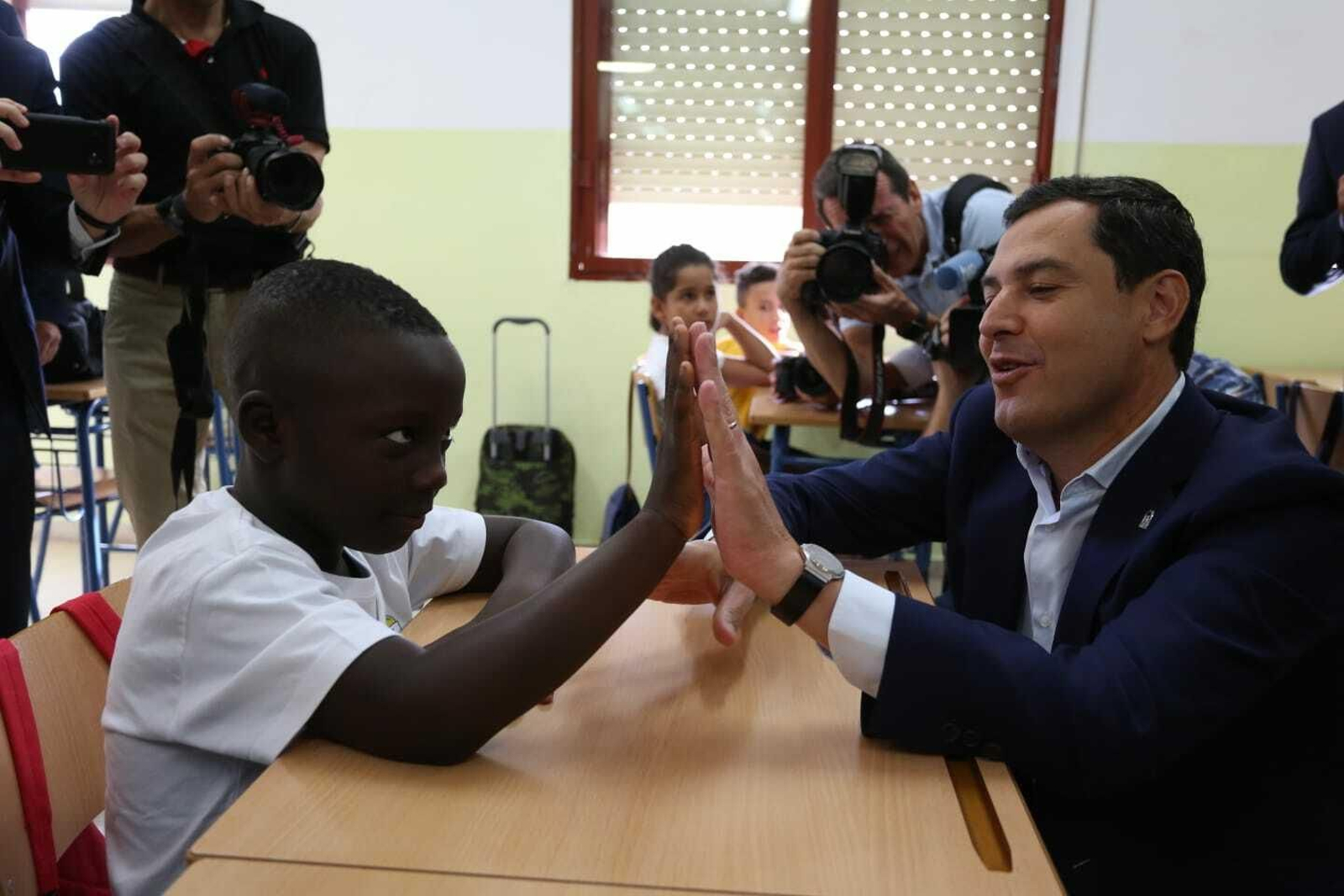 Juanma Moreno choca la mano a un alumno de 3º del CEIP Manuel Altolaguirre.