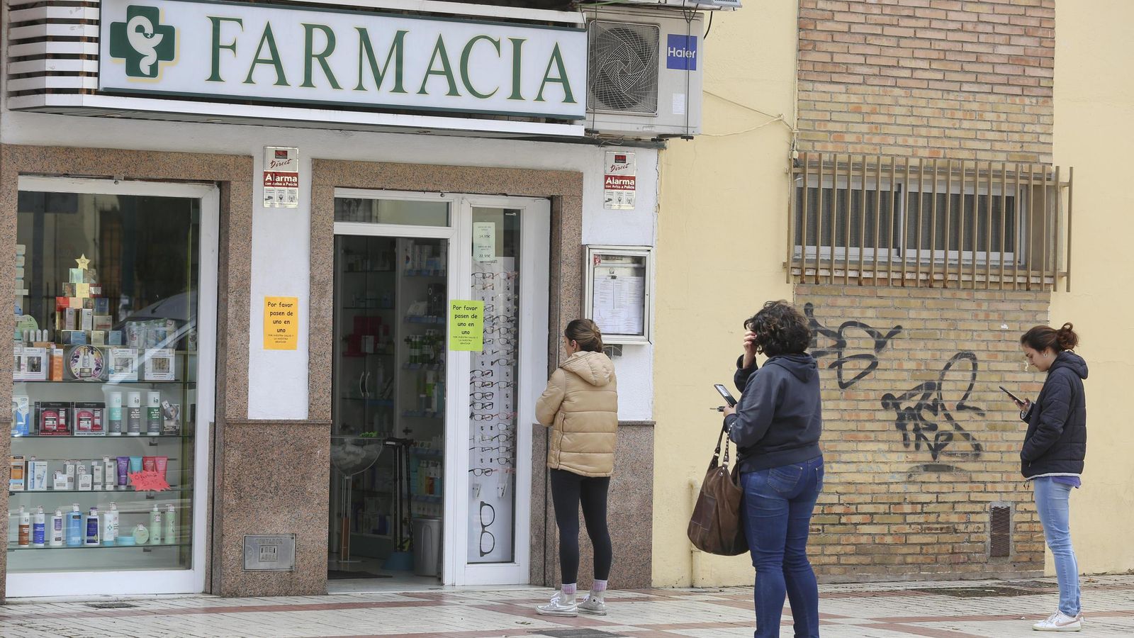 Clientes esperan su turno en la puerta de una farmacia.