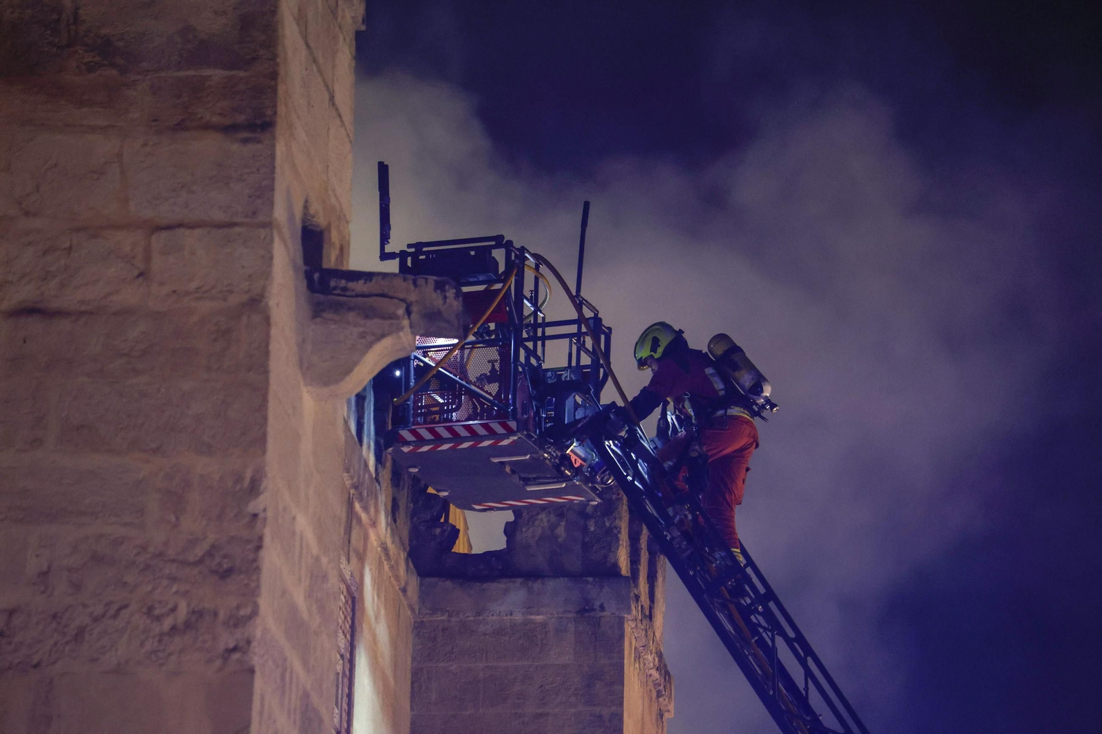 Un bombero sube por una grúa durante el incendio de la Mezquita-Catedral