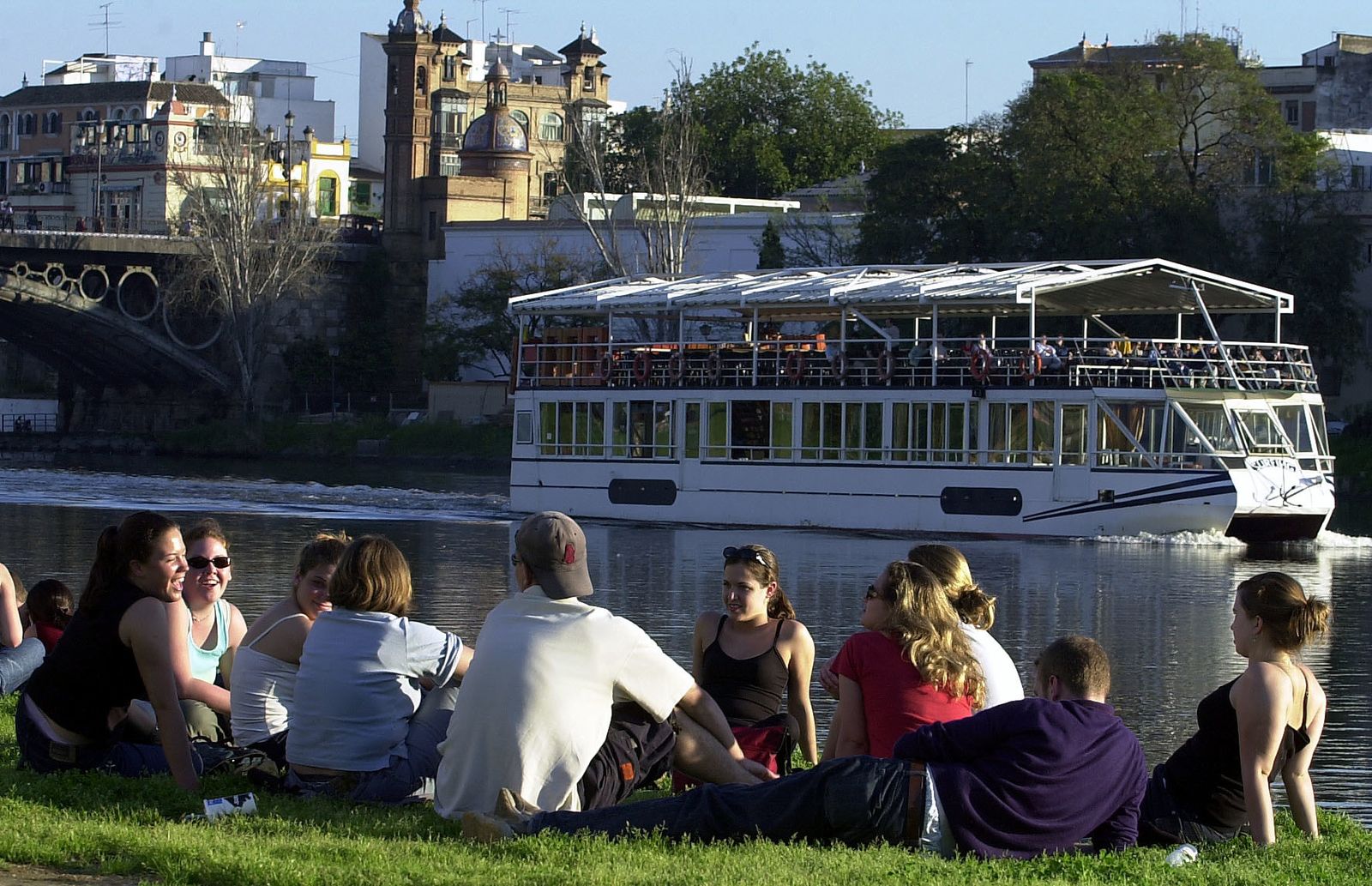 Varios jóvenes se concentran en una de las orillas del río Guadalquivir.