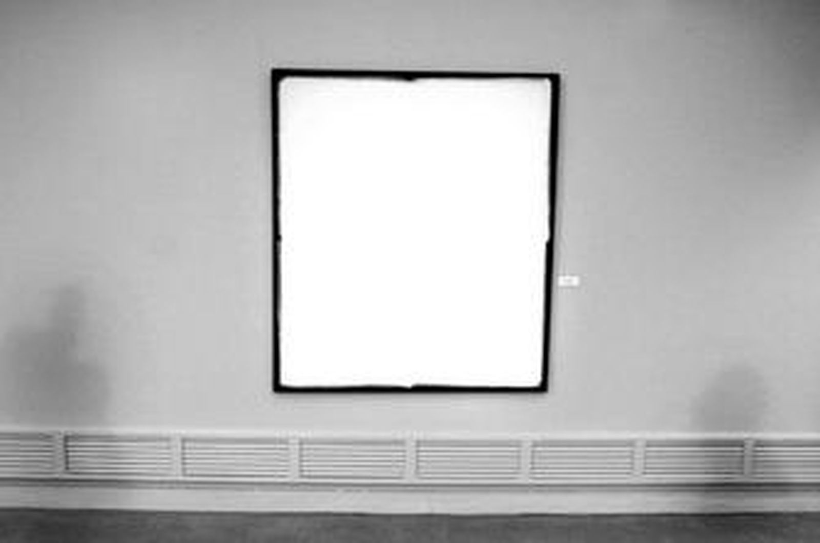 El artista posa sonriente entre dos cuadros.