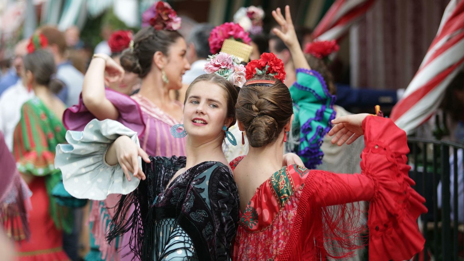 Dos jóvenes bailan sevillanas en la puerta de una caseta.
