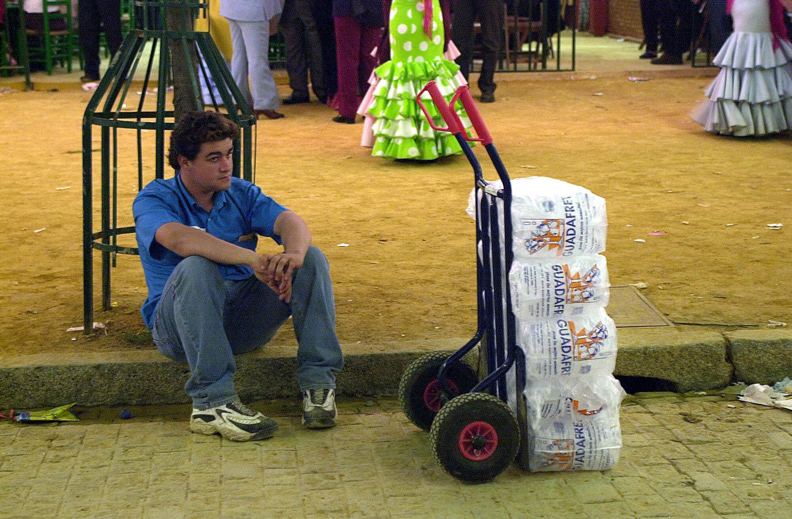 Un repartidor de hielo descansa sentado en un bordillo.