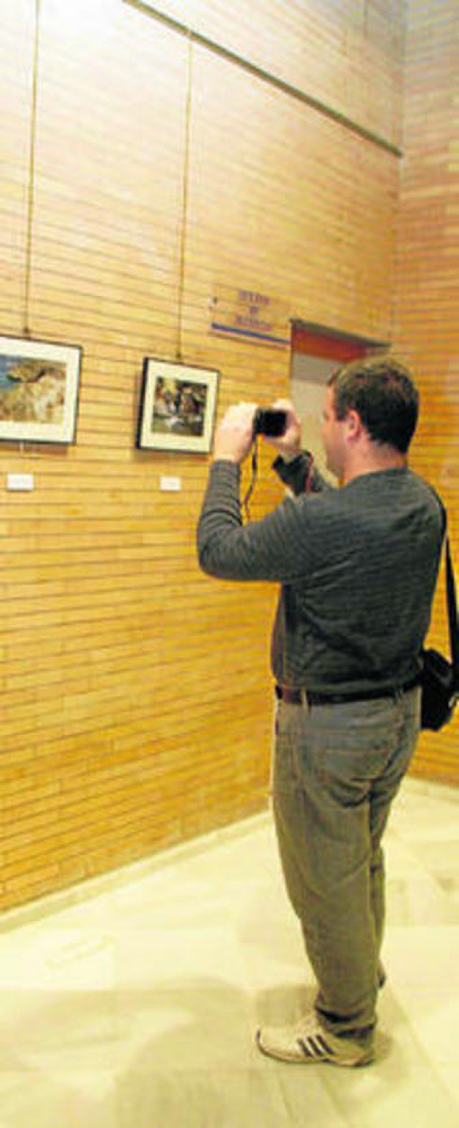 Un aficionado a la fotografía fotografiando la exposición de fotografías.