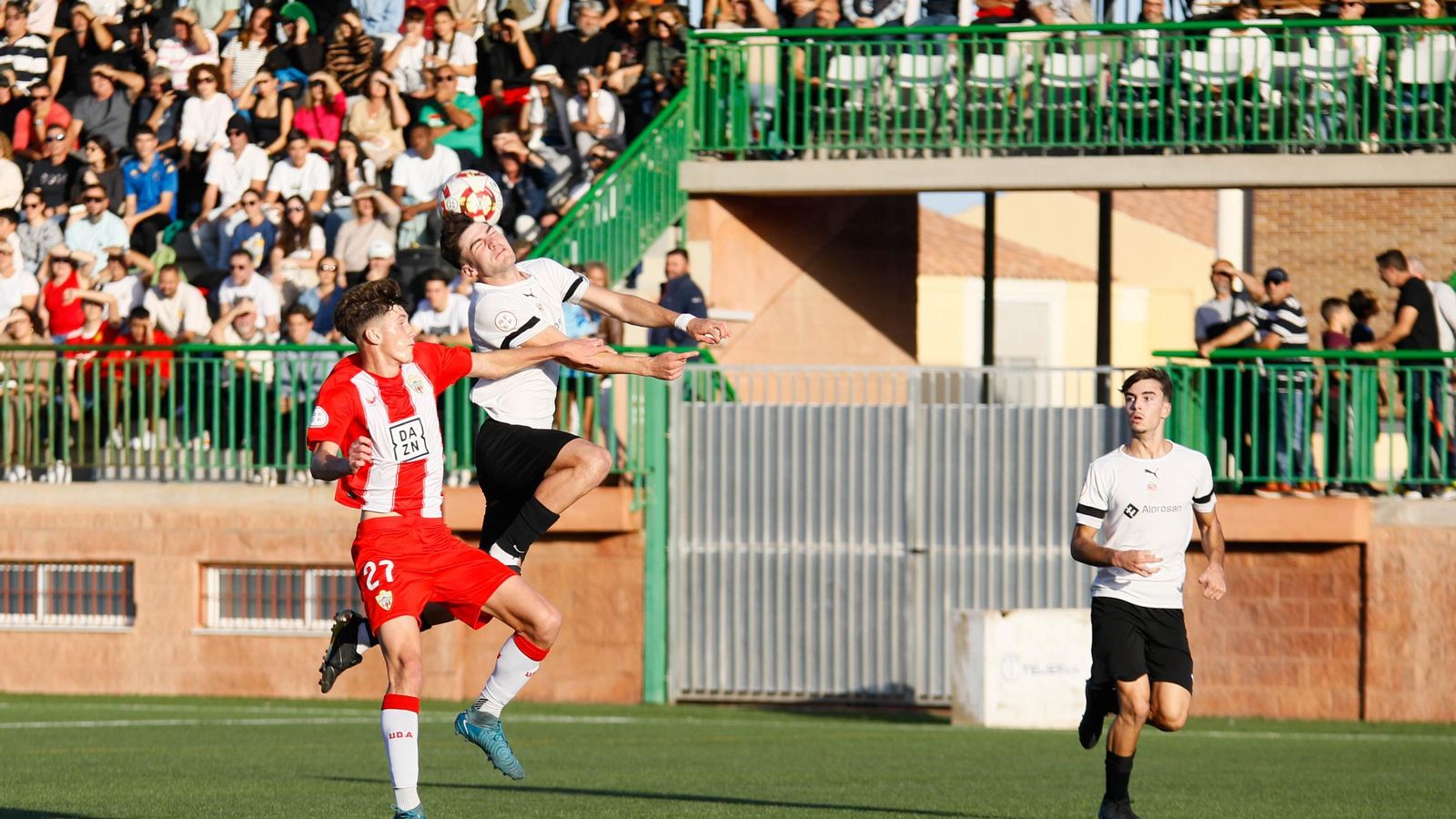 El rojiblanco Fran Rodríguez pugna con un rival por un balón aéreo durante el derbi almeriense.