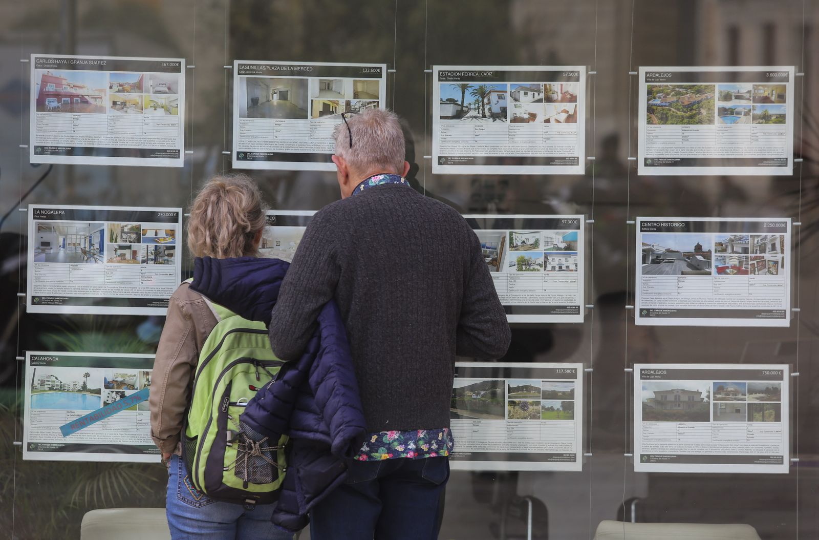 Dos personas observan el escaparate de una inmobiliaria en Málaga.