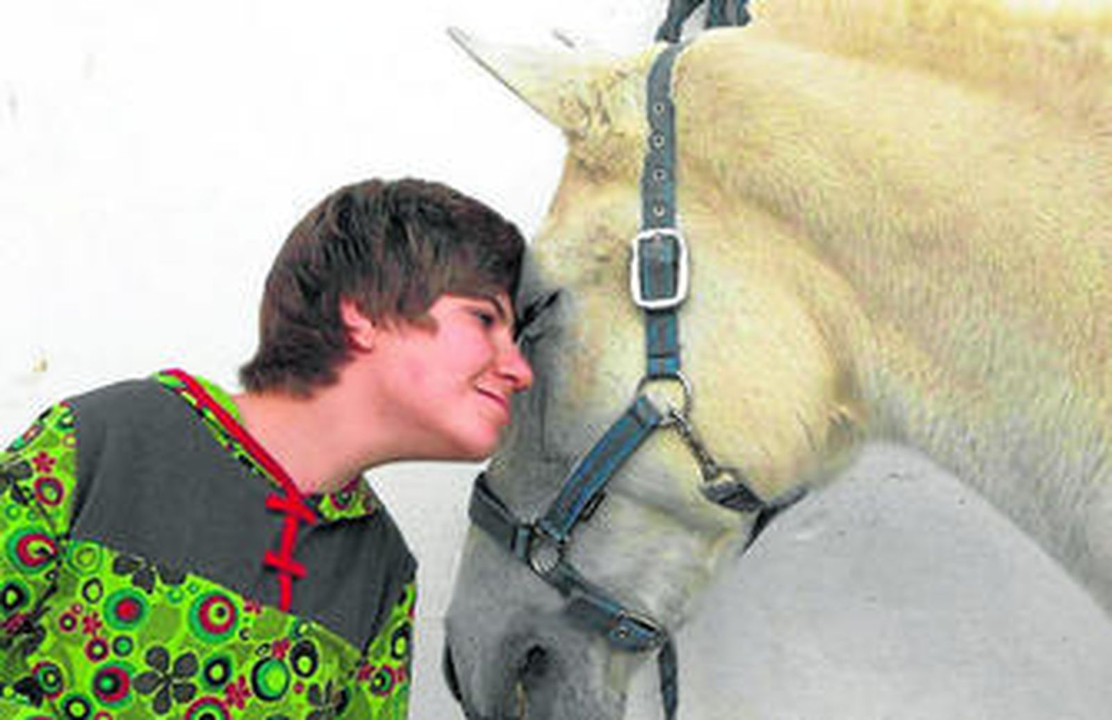 Una joven junto a un equino en una sesión de hipoterapia.