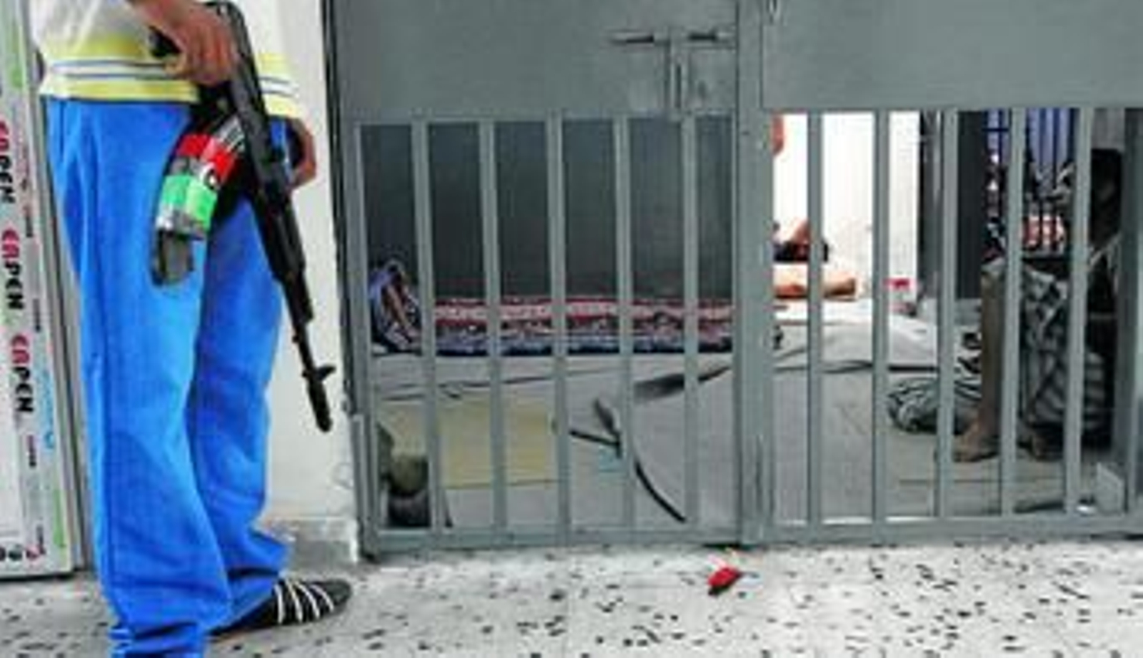 Un guarda vigila a prisioneros sospechosos de luchar con Gadafi en Trípoli.