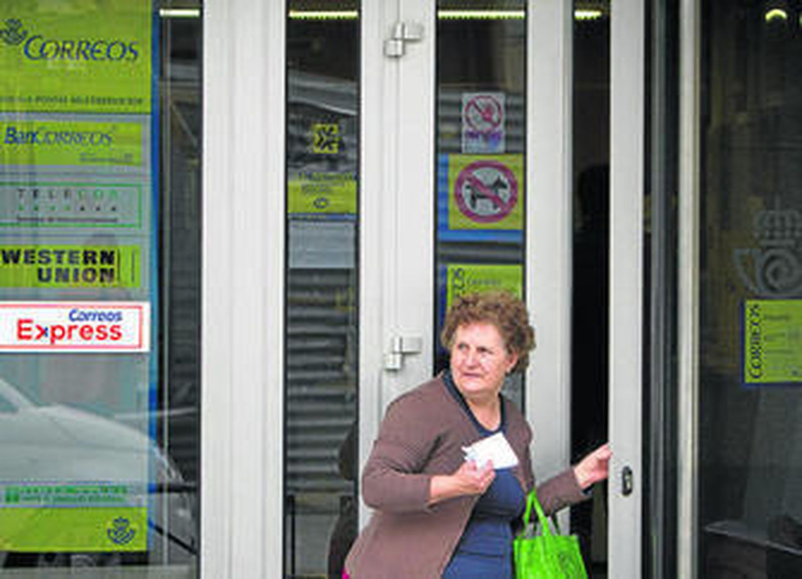 Una señora sale de las oficinas situadas frente al ambulatorio de El Lugar.