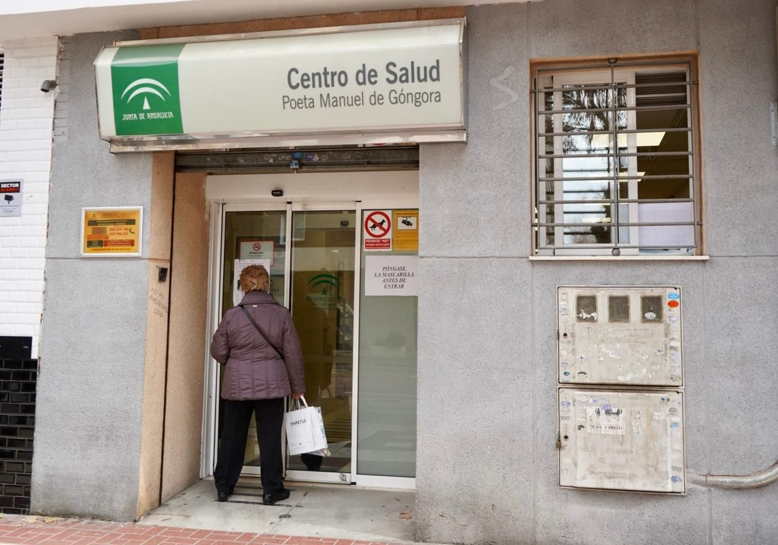 Una usuaria lee un cartel a las puertas de un centro de salud de Granada capital