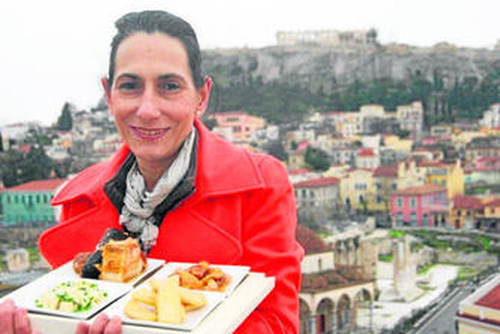 Margarita Barros sostiene una bandeja con berza, pringá, paniza y huevos de fraile, cocinados en su taller, ante la Acrópolis.