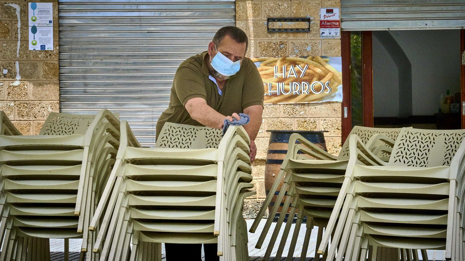 Un hostelero limpia minuciosamente las sillas para instalar la terraza.