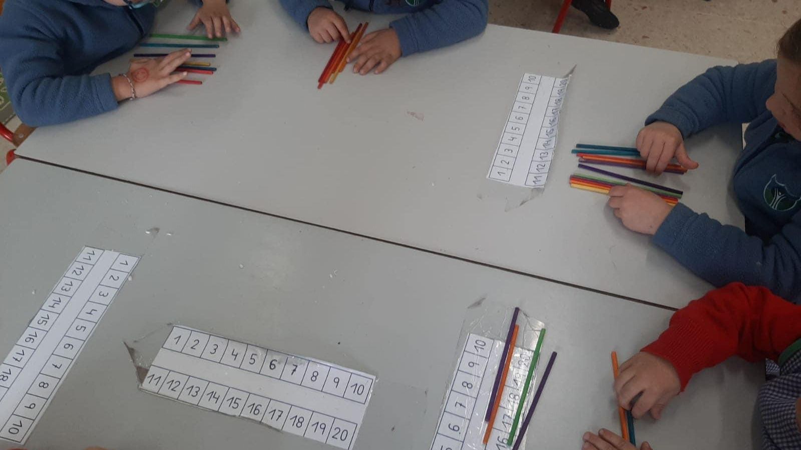Niños en clase aprendiendo a contar con palillos.