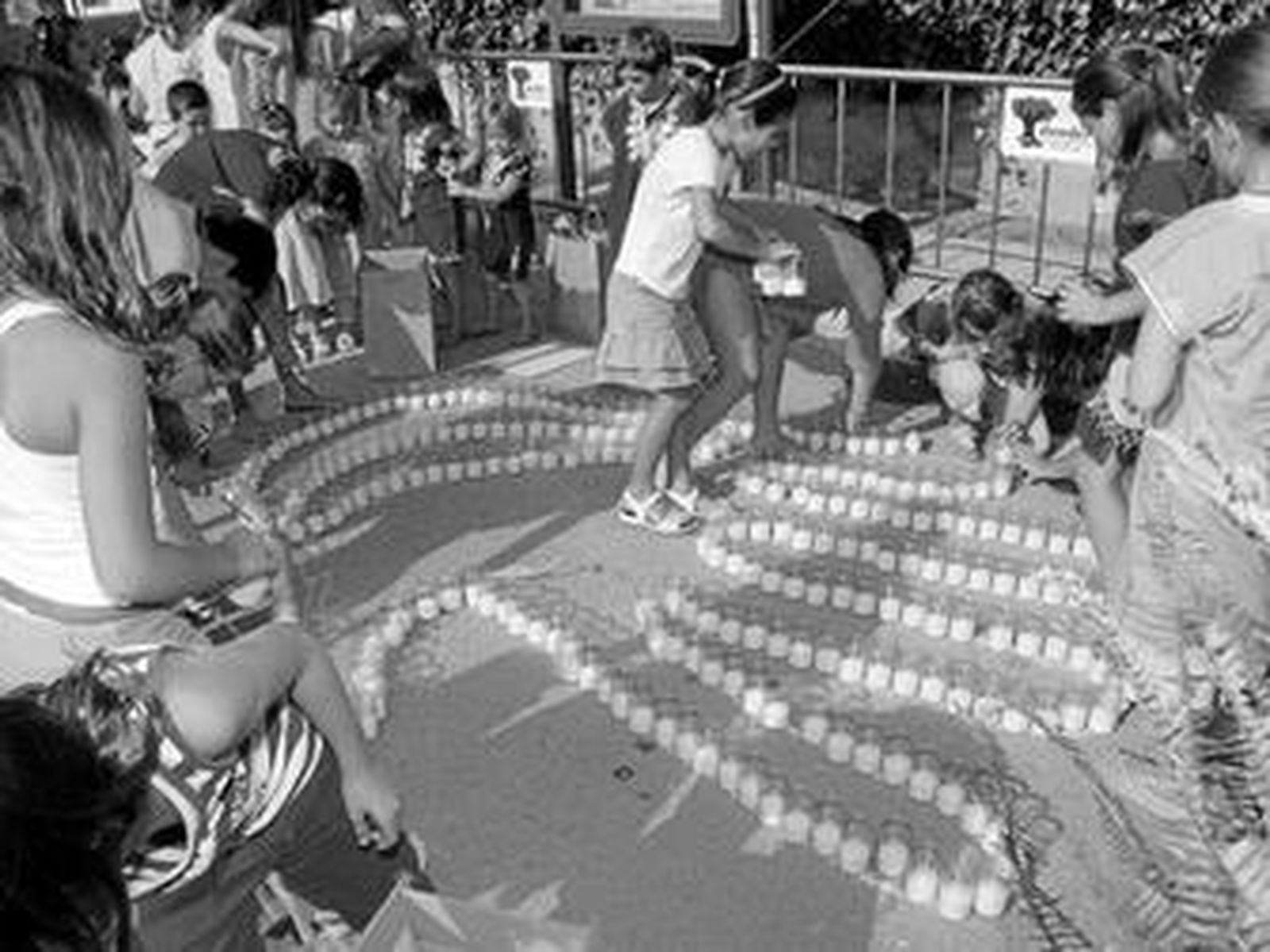 Unos niños forman la palma de una mano con velas, horas antes del anochecer.