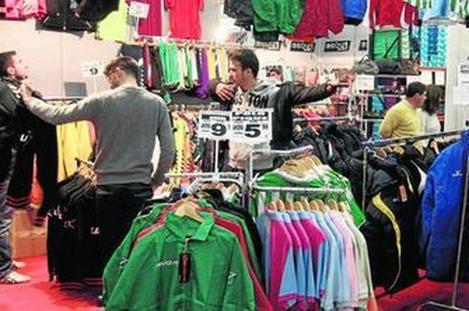 1. Un joven se prueba una cazadora mientras otro comprueba el precio. 2. Uno de los expositores de la feria con cuadros para decoración a 5 euros. 3. Distintas ofertas de abrigos por 80 y 50 euros.