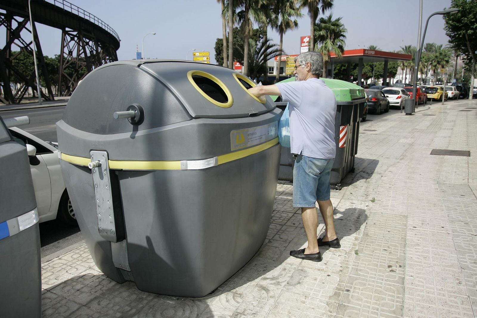 Un hombre deposita sus envases en el contenedor amarillo.