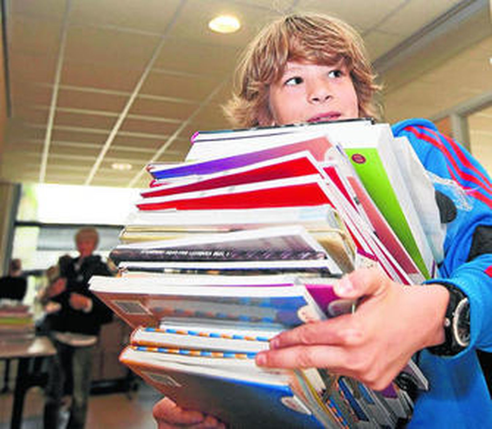 Un alumno apila los libros a estrenar en el nuevo curso.