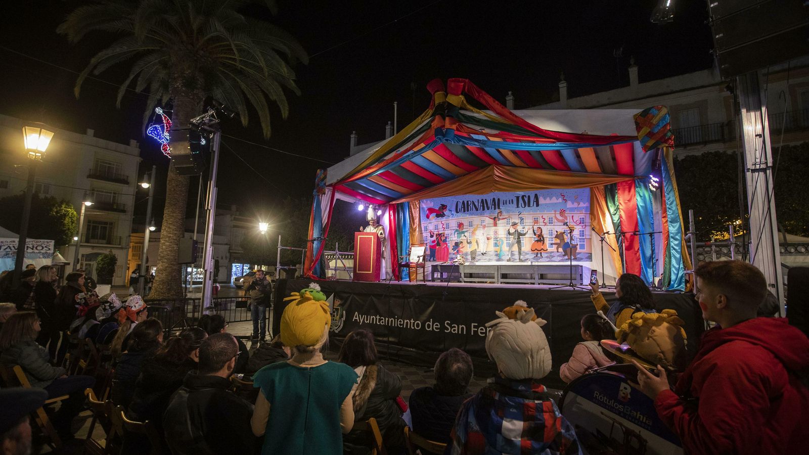 Componentes de la chirigota 'Los de la cantera', de Juan Rivero, observan el pregón junto al público.