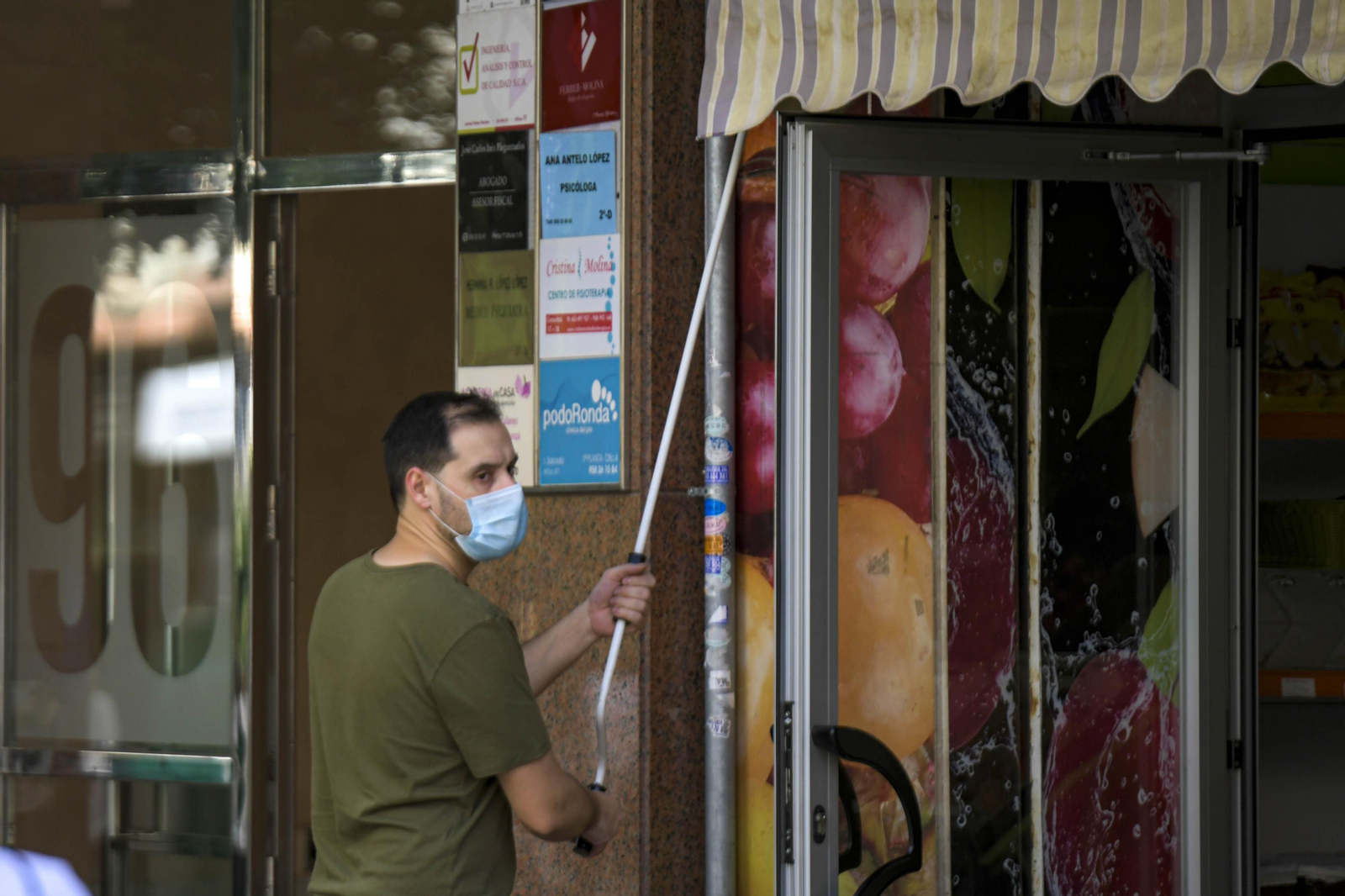 Un comerciante abre la persiana de su establecimiento