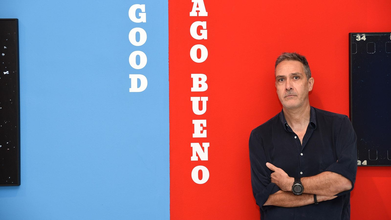 El fotógrafo Santiago Bueno posa frente al cartel de la exposición.