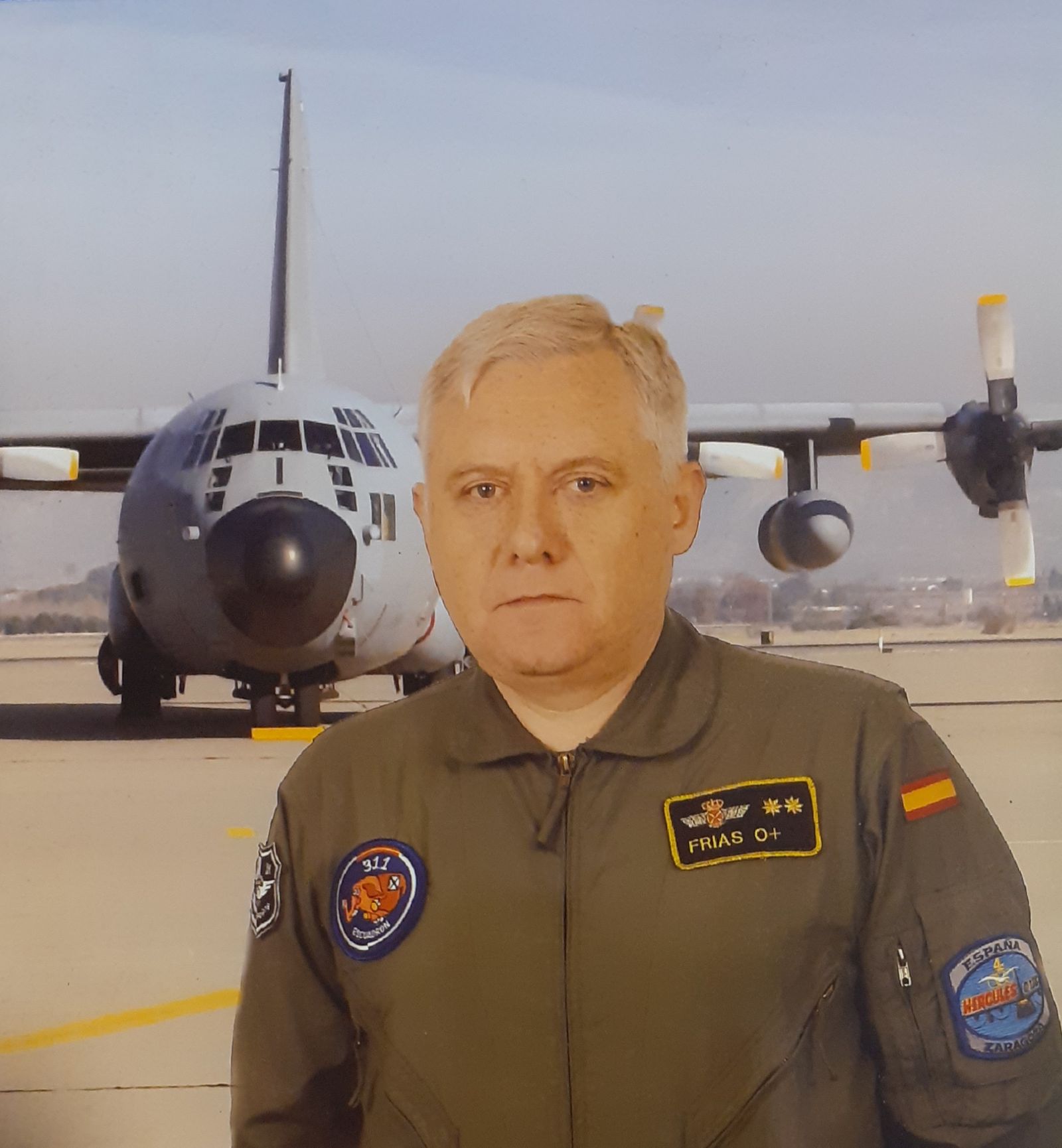 Con su indumentaria del Ejército del Aire, con un avión militar al fondo.