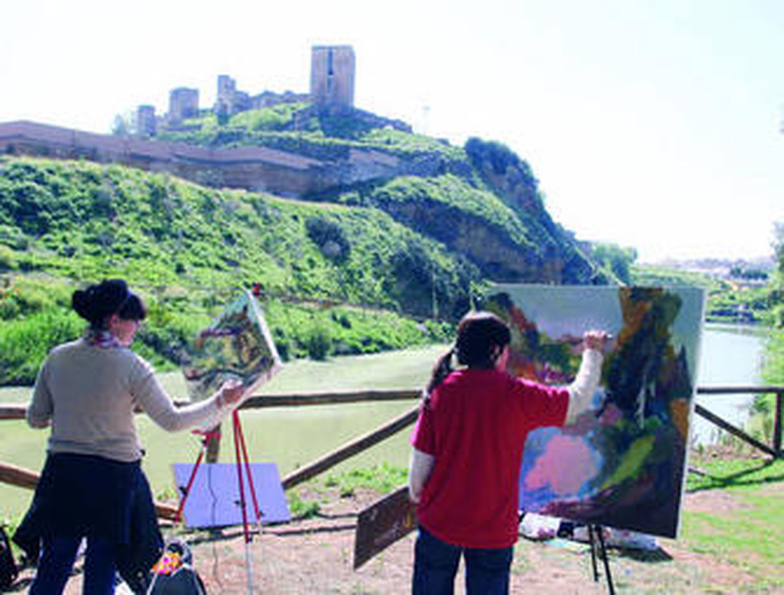 Dos alumnas de Bellas Artes pintan ante el espectacular paisaje del Guadaíra bajo el Castillo de Alcalá.