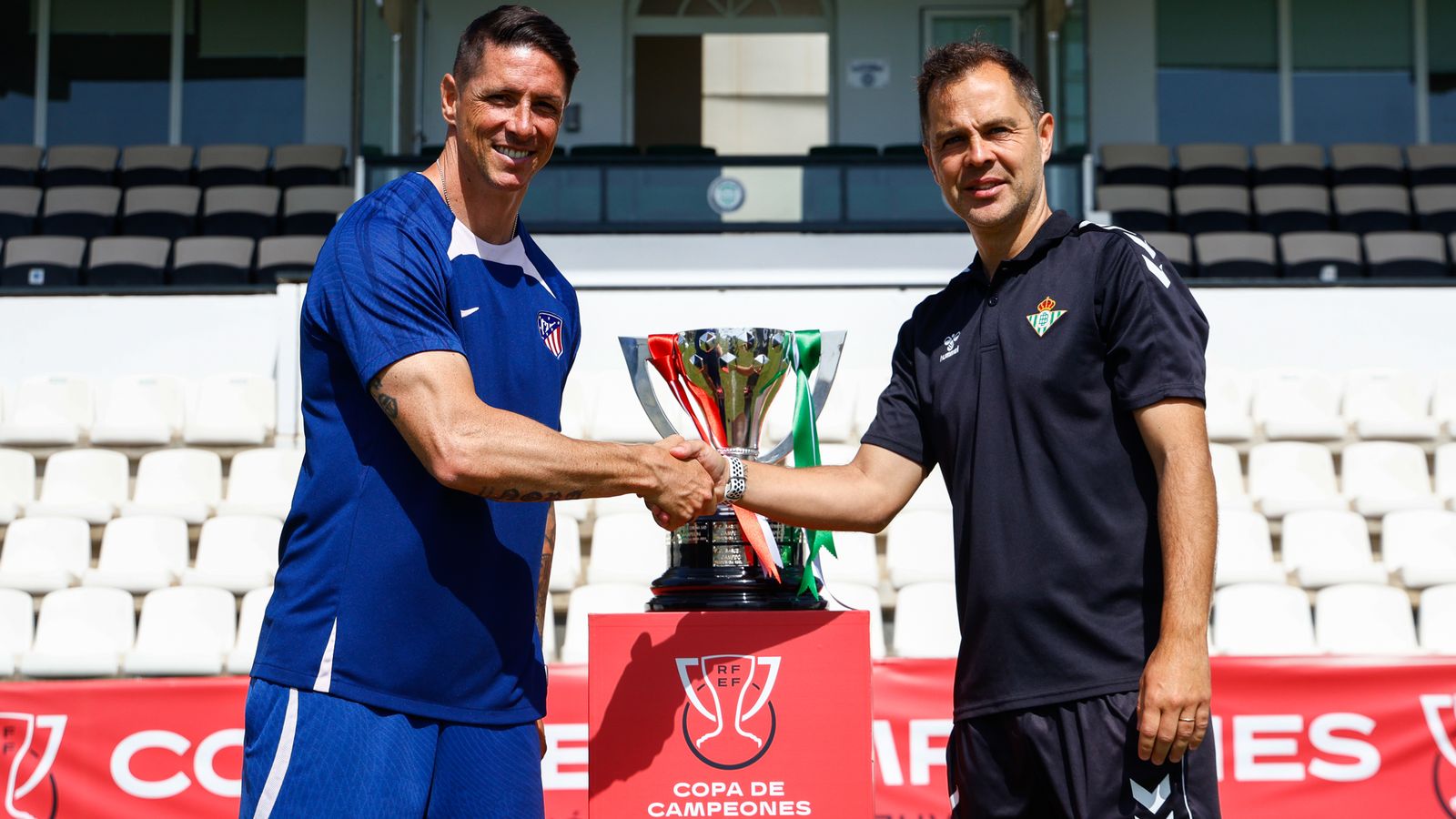 Los entrenadores de ambos equipos, Fernando Torres y Dani Fragoso, posan amistosamente junto al trofeo de la Copa de Campeones.