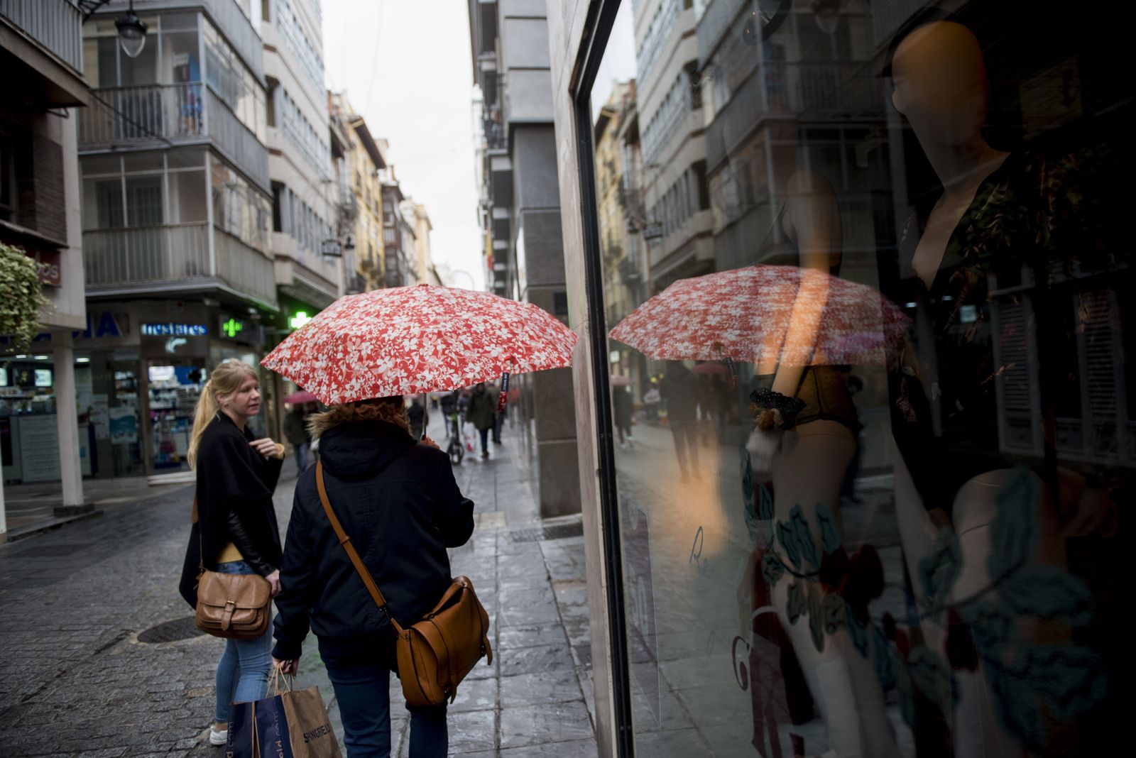 Una mujer se protege de la lluvia con un paraguas.