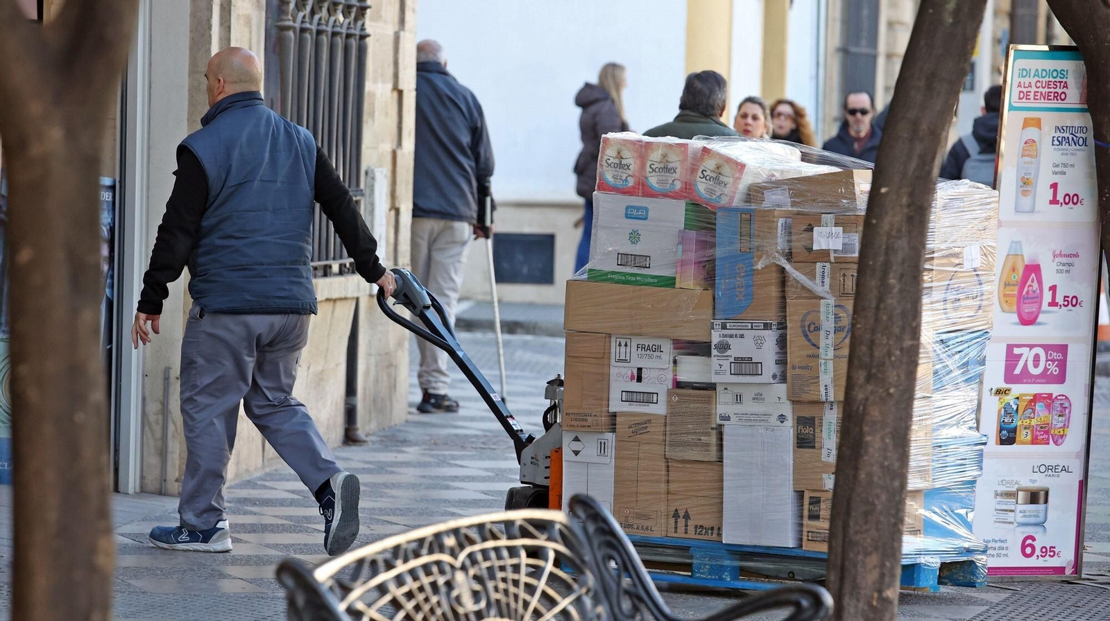 Un trabajador con una carretilla cargada para la entrega de un pedido en un negocio del centro.