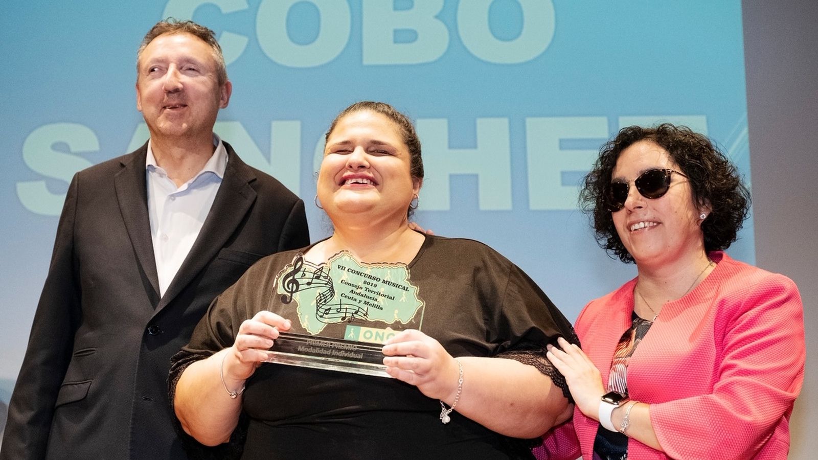 Teresa Cobo recibiendo el premio de la mano de los responsables de la Once en Andalucía.