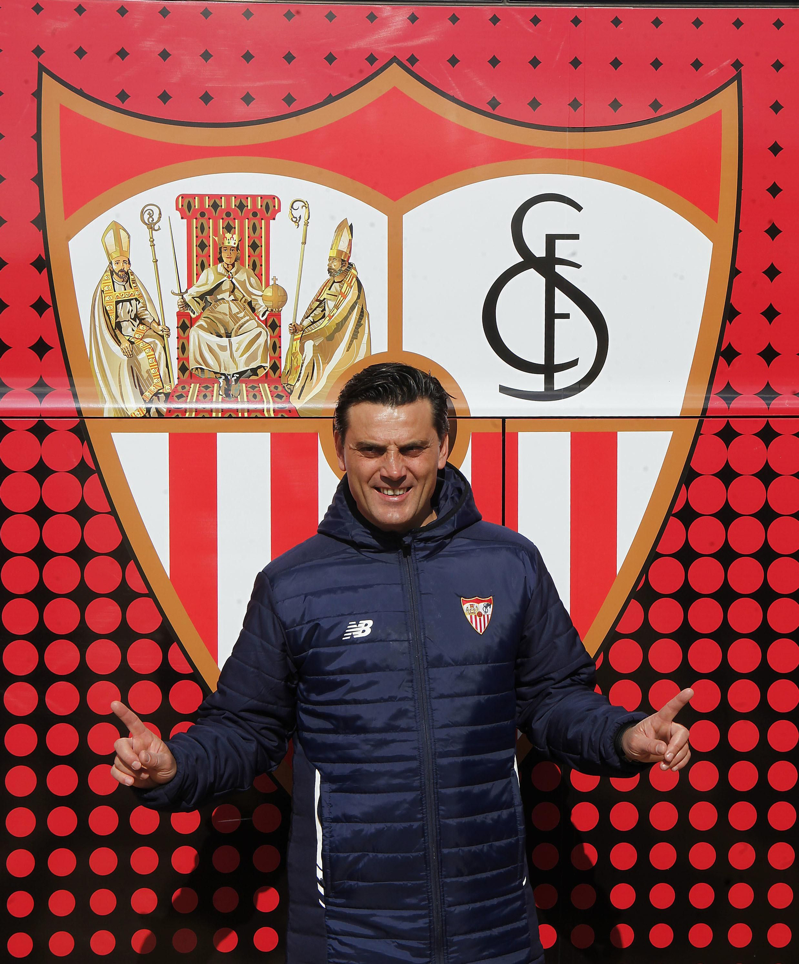 Montella posa junto al escudo del Sevilla en los nuevos autobuses