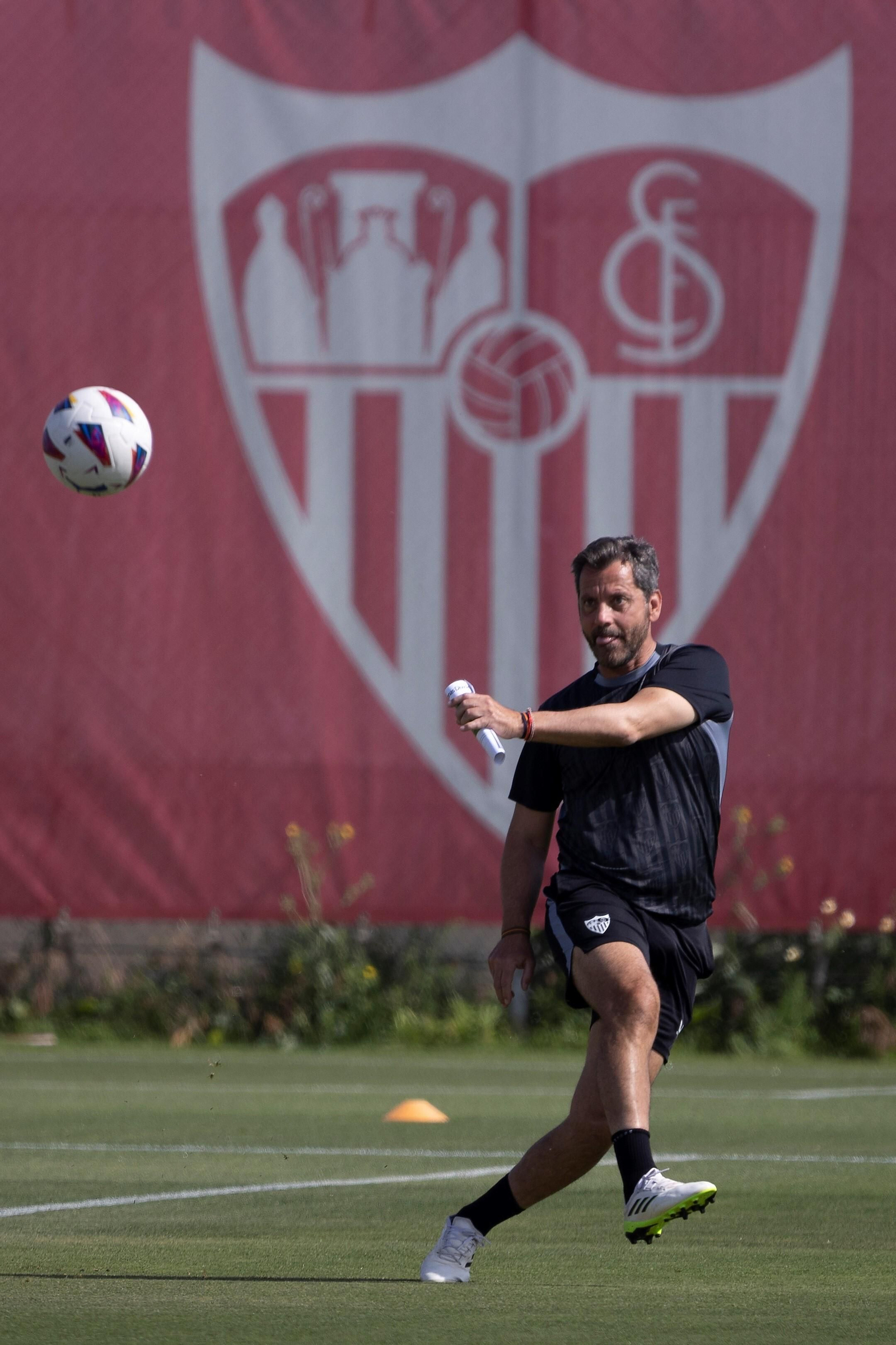 Quique golpea el balón con el escudo del Sevilla al fondo.