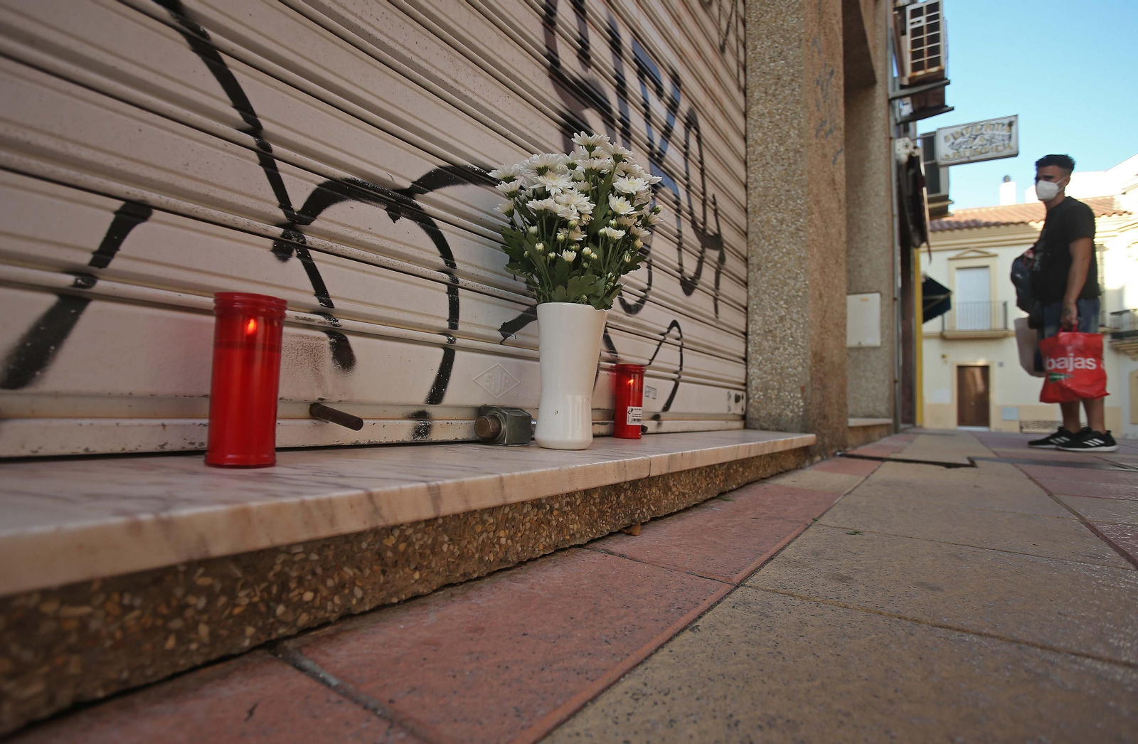 Flores y velas en la puerta del establecimiento en la calle Teniente Serra.