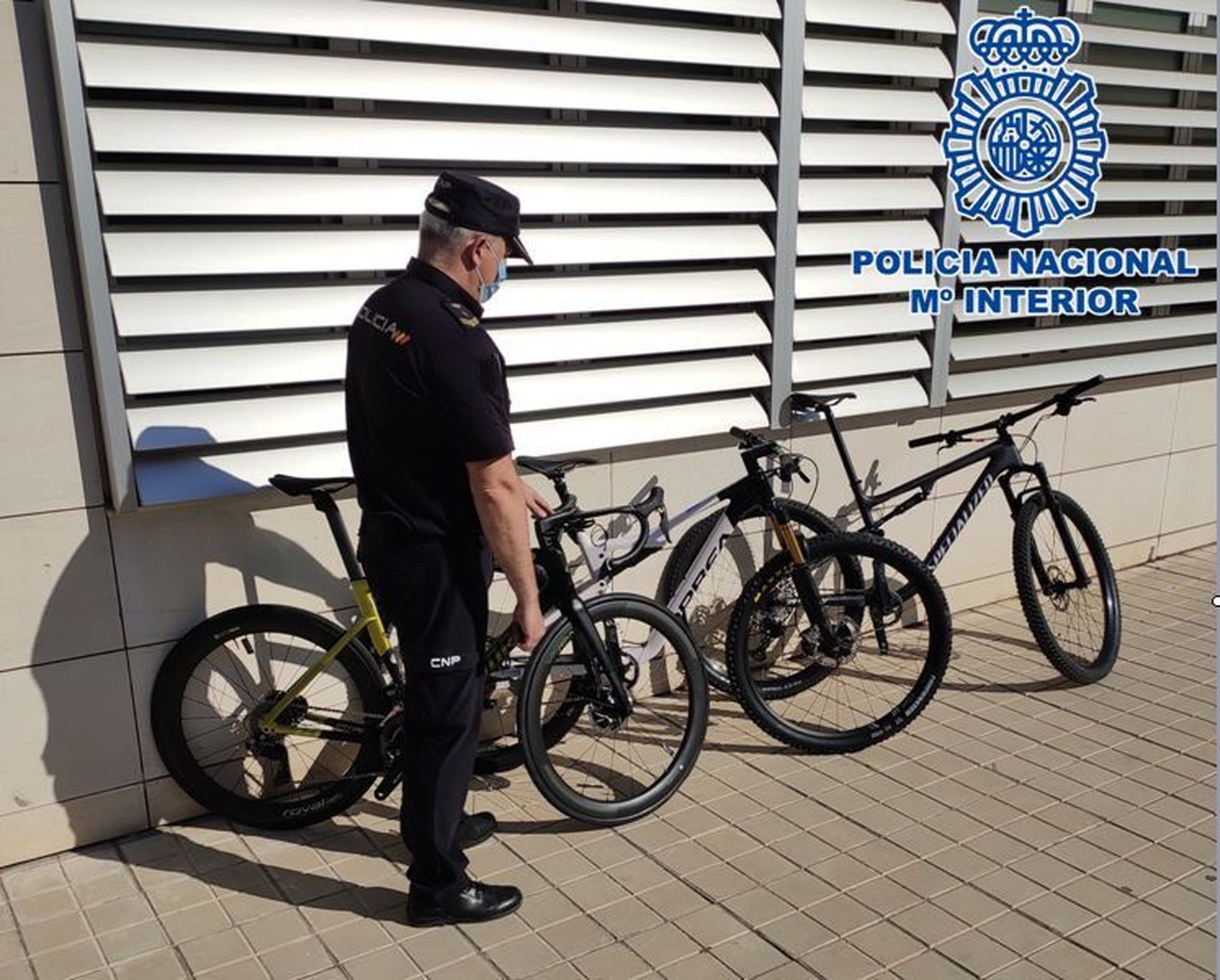 Un agente de la Policía Nacional junto a las tres bicicletas robadas recuperadas.