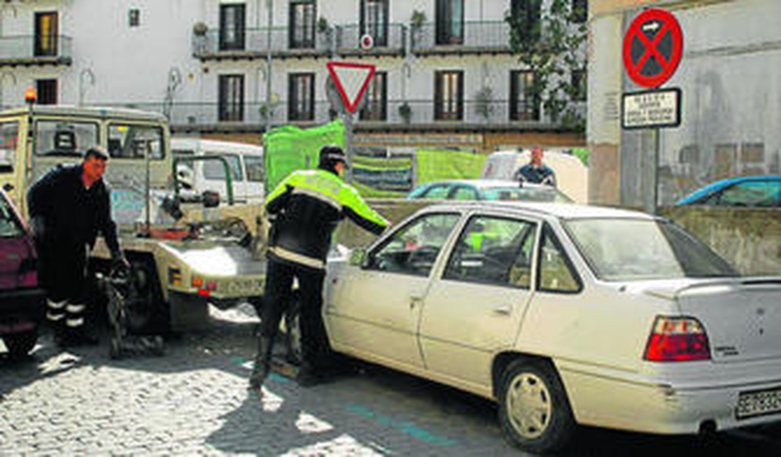 Un policía multa a un coche antes de que sea retirado por la grúa.