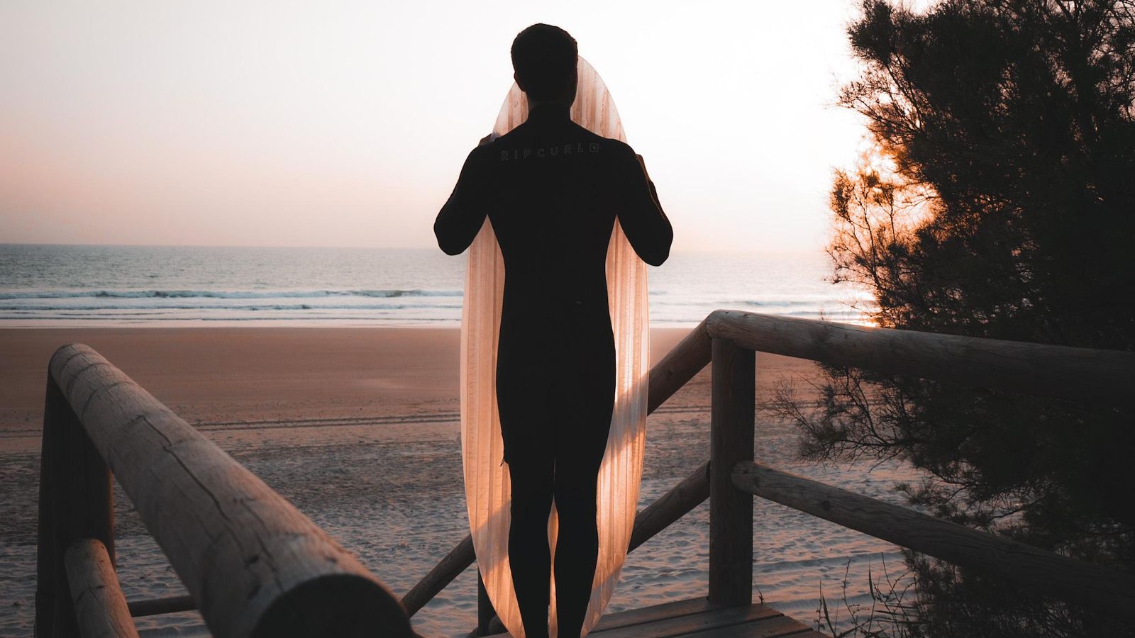 Un surfista con una tabla de plástico reciclado de Trash Peak.