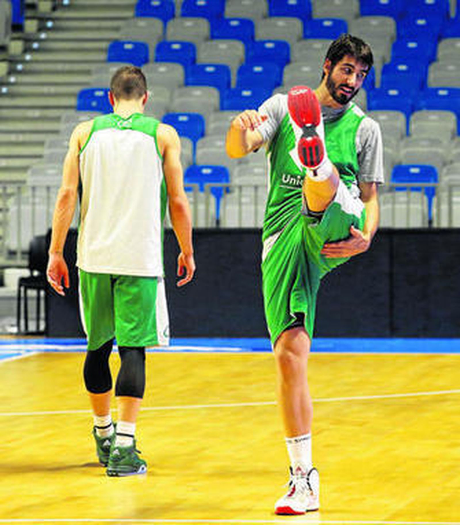 Dani Díez realiza estiramientos con Nedovic al fondo.