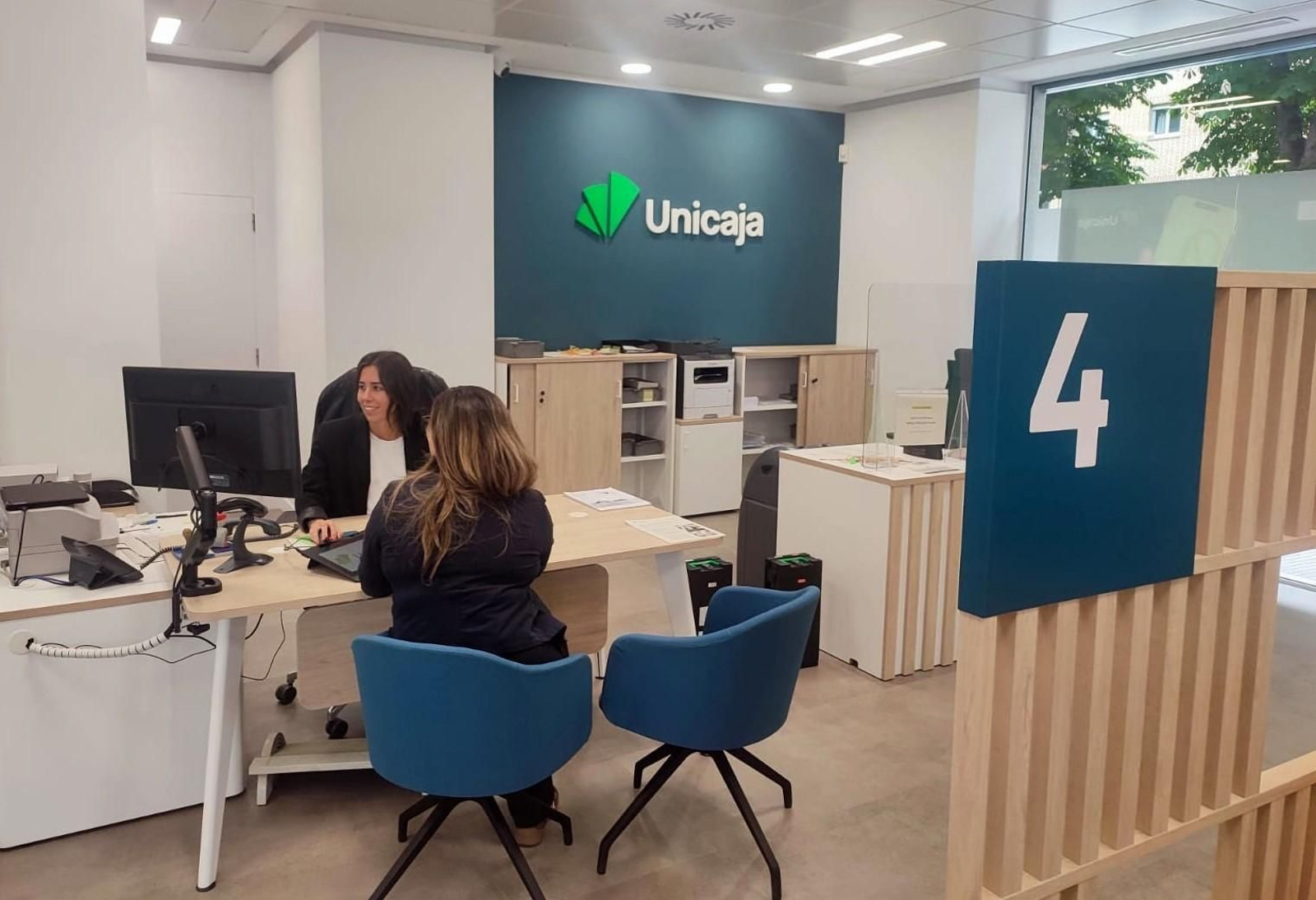 Personal de Unicaja atendiendo a una clienta en una de sus oficinas