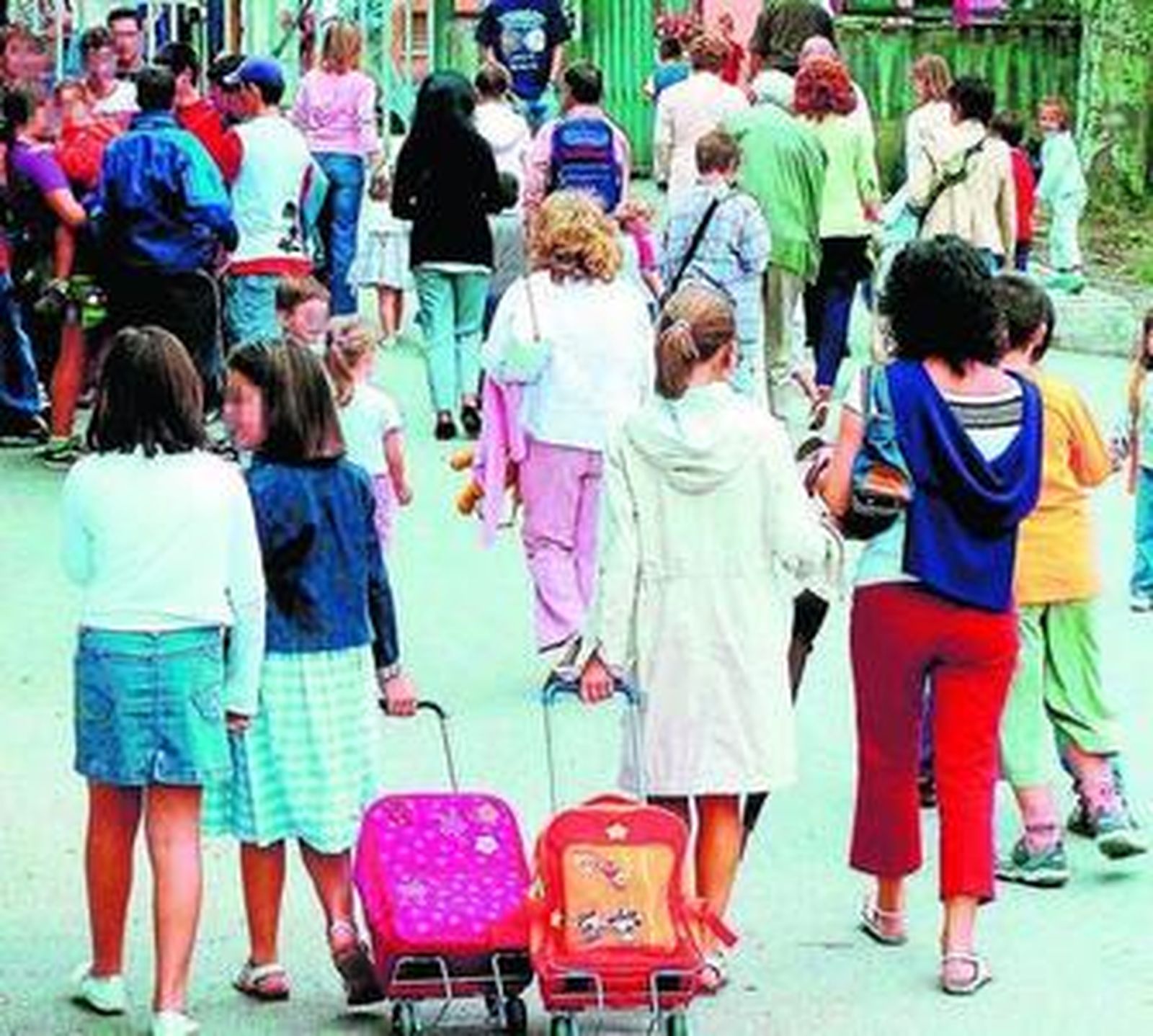 Un grupo de alumnos y sus padres, a la entrada de un colegio.