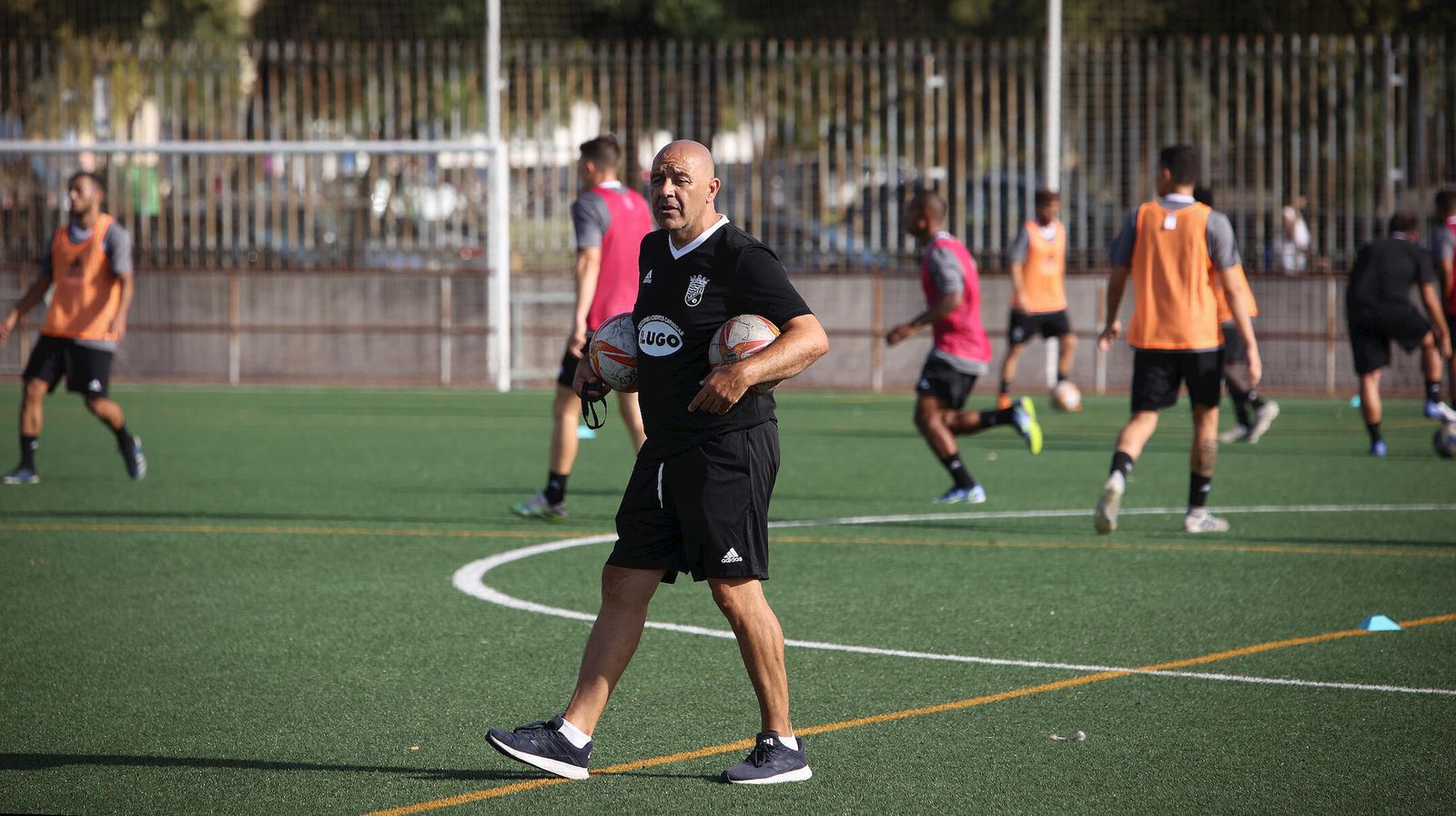 Paco Peña, técnico azulino, porta dos balones en un entrenamiento en La Granja.