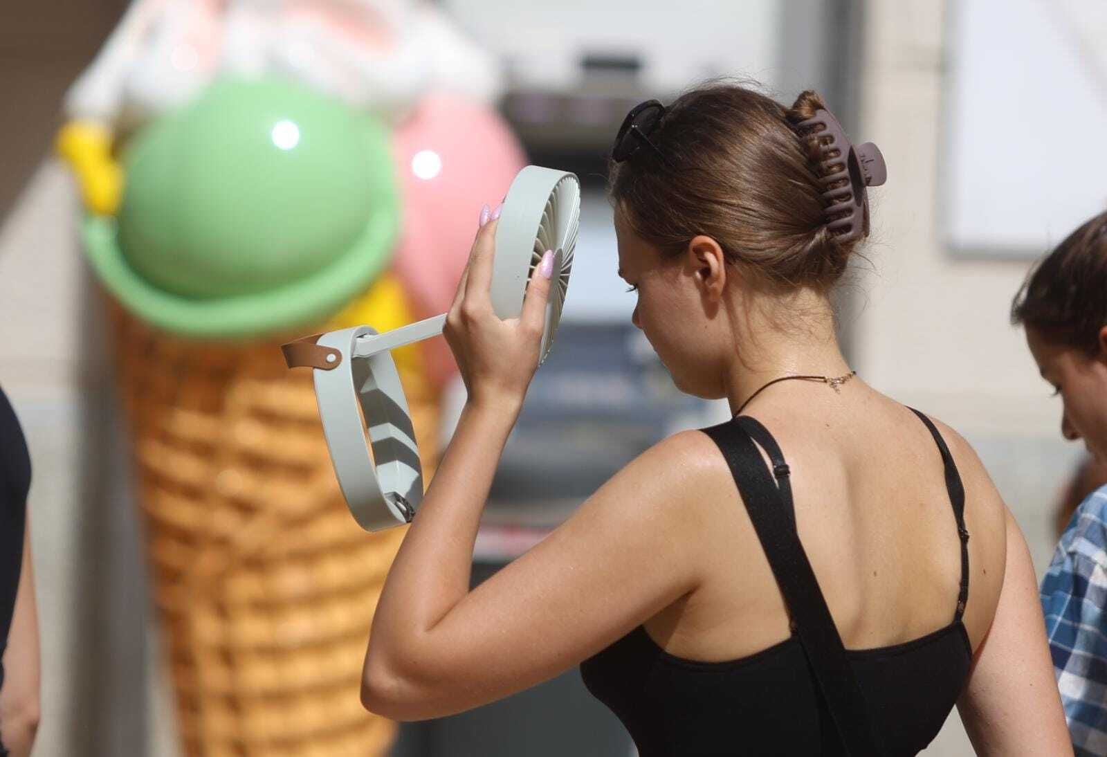 Una viandante combate el calor con un ventilador portátil en Málaga.