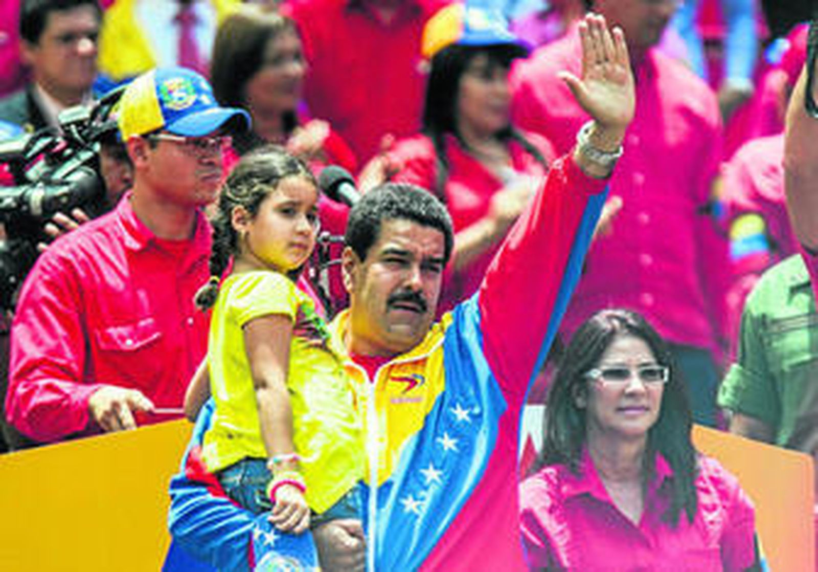 Nicolás Maduro, con su hija en brazos, saluda al lado de su mujer, Cillia Flores, a miles de seguidores, ayer en Caracas, tras inscribirse como candidato.