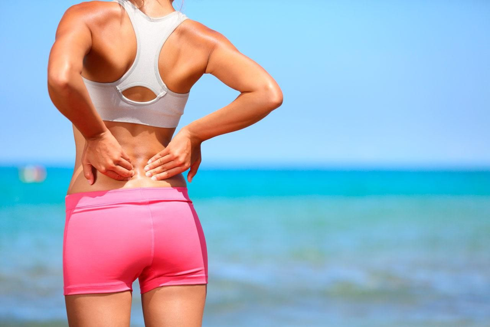 Una mujer se toca la zona baja de la espalda.