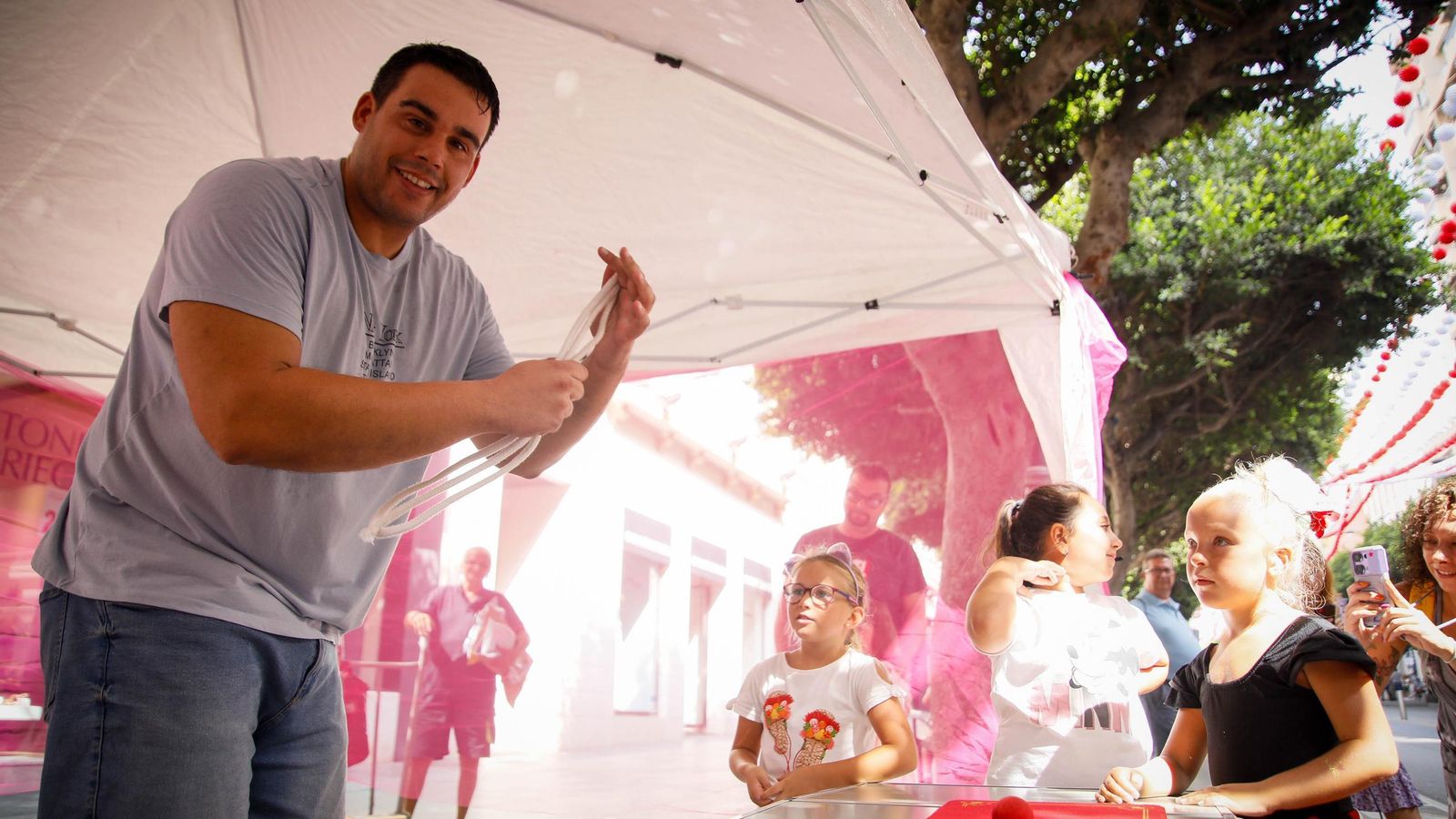 Uno de los magos realiza un truco con cuerdas de distintos tamaños ante la atenta mirada de los jóvenes asistentes.