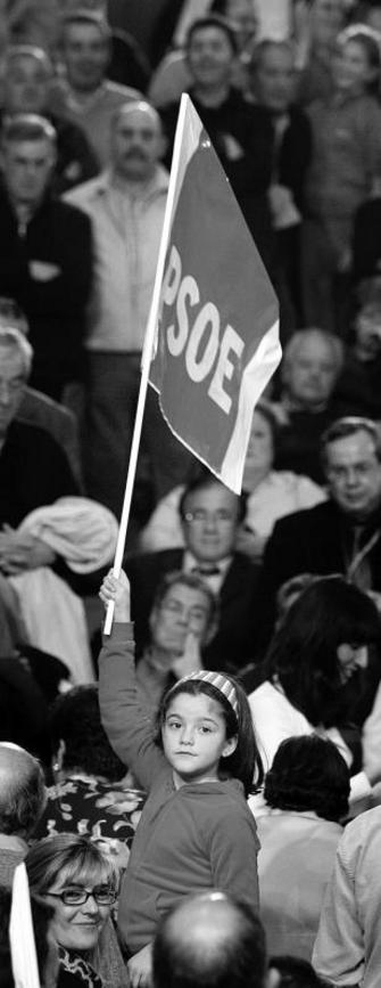 Una niña sujeta una bandera de apoyo al PSOE en el auditorio del Palacio.